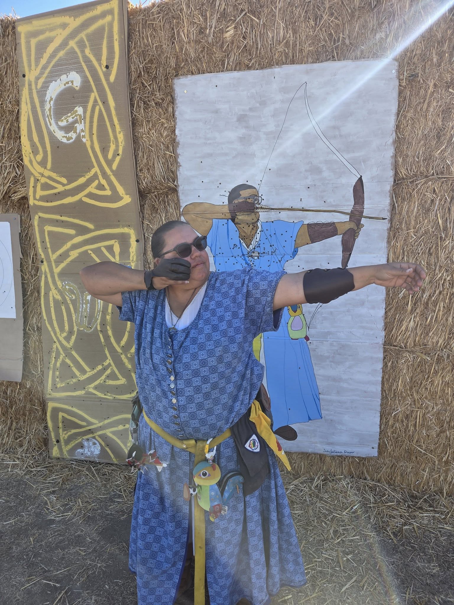 Archer standing in front of a target painted to look like her.