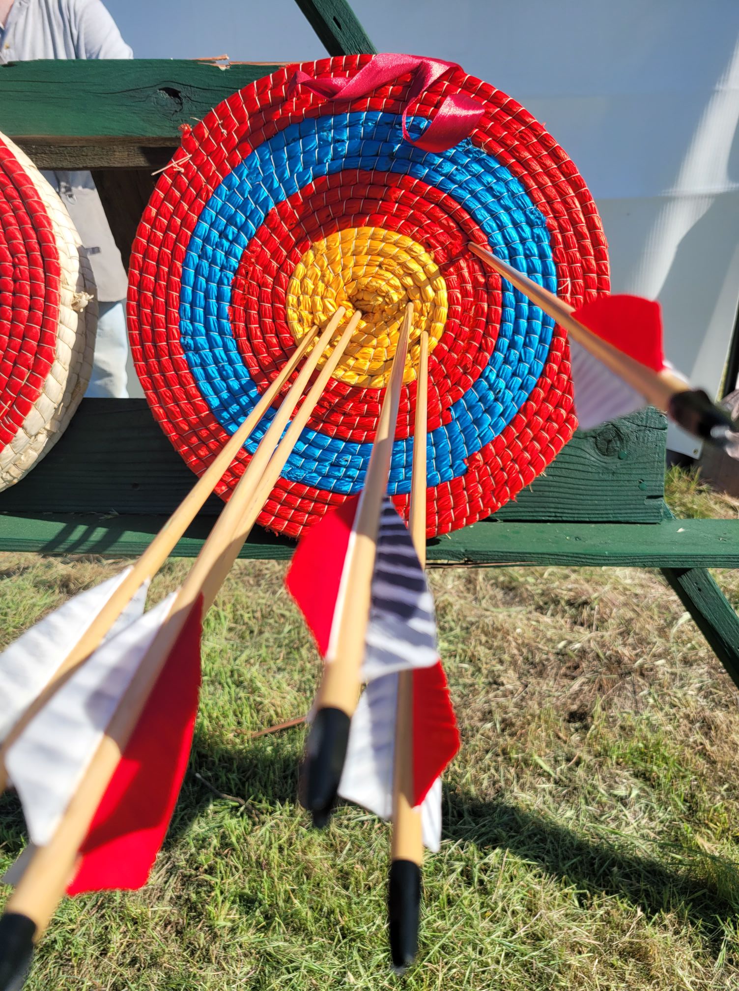 Archery Target with five arrows in the bull's eye and one in the Red.